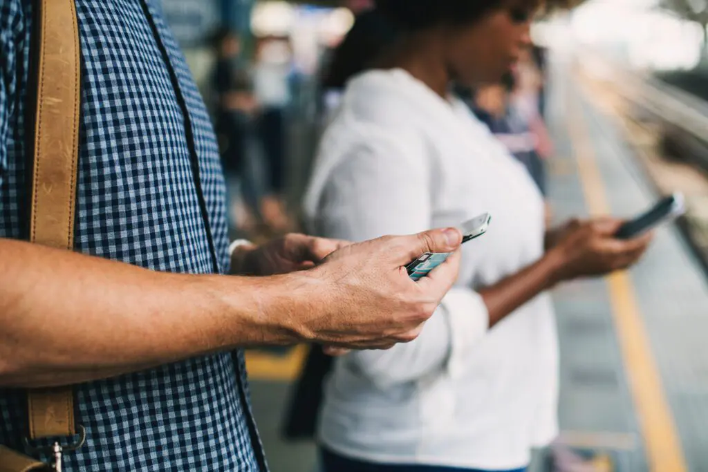 Digital identity verification and the Canadian economy: Photo of hands holding smartphones on a train platform
