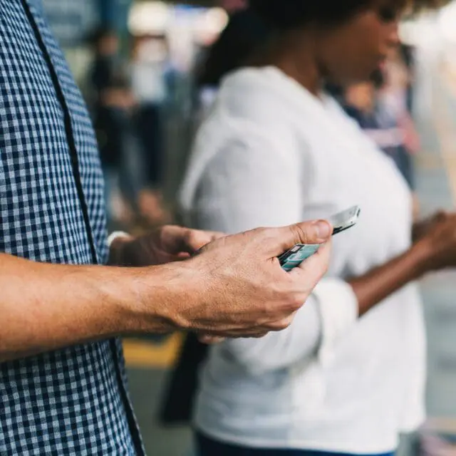 Digital identity verification and the Canadian economy: Photo of hands holding smartphones on a train platform