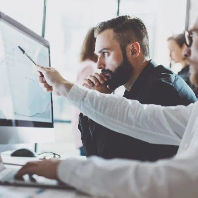 Digital ID and cyber security: Two men working in finance look at a computer screen