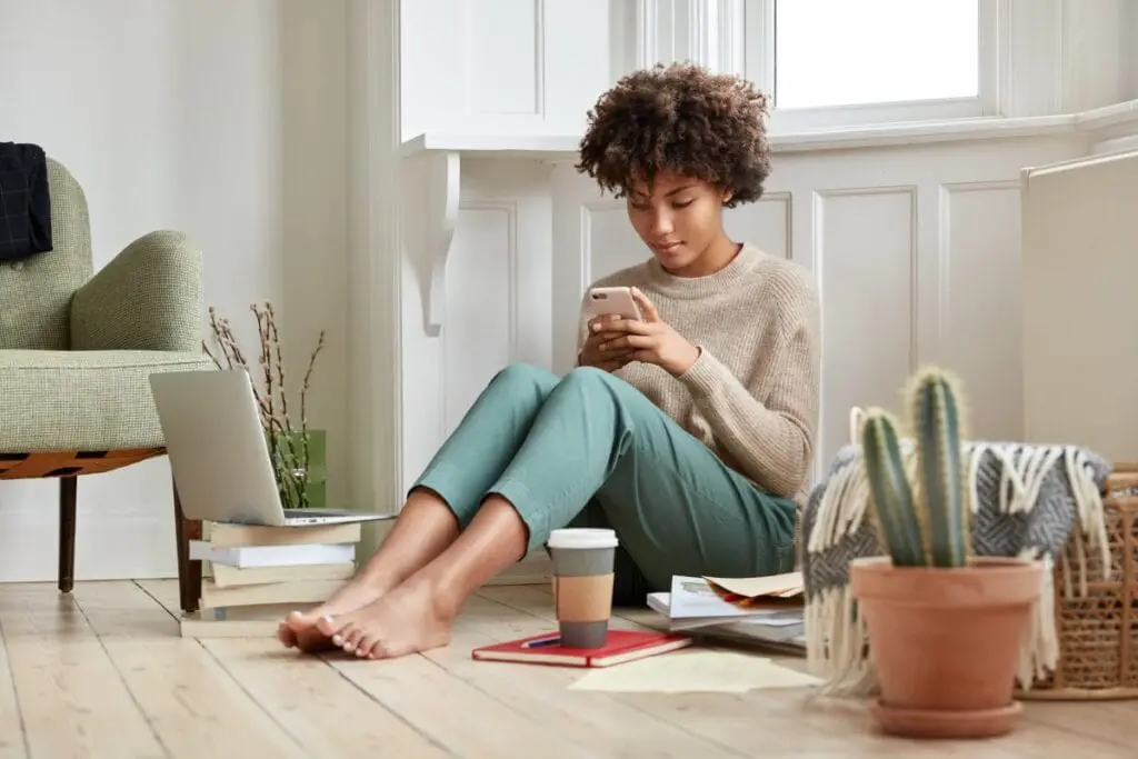 A seated young woman looks at her smartphone, updating her data security.
