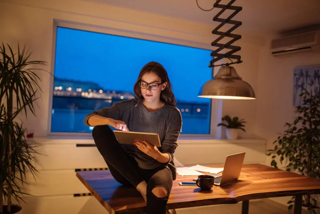smiling woman uses a tablet. Consumers are advised to watch out for e-transfer and other scams.