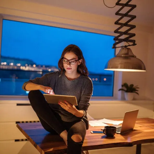 smiling woman uses a tablet. Consumers are advised to watch out for e-transfer and other scams.