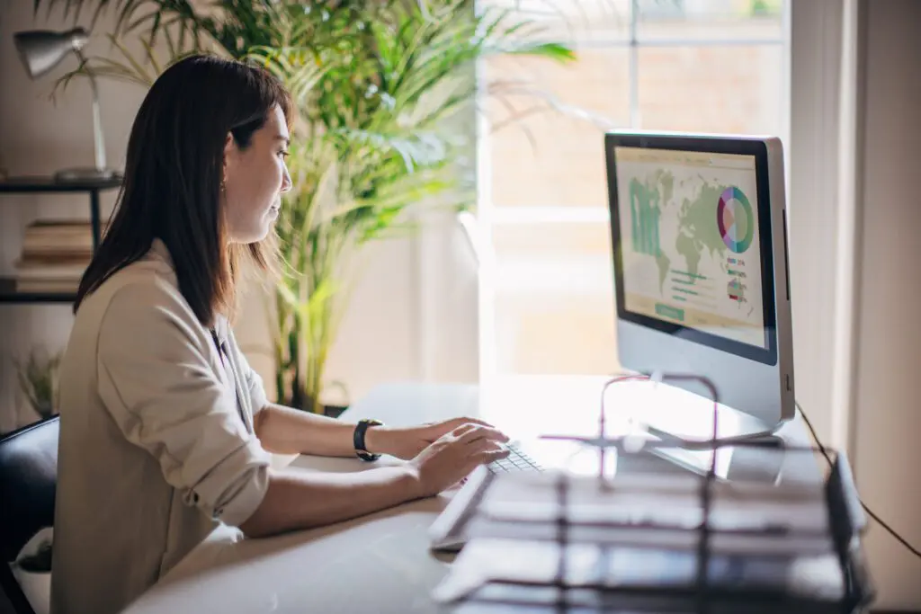 Woman works on desktop with world map on the screen, as digital currency creates a finance transformation.