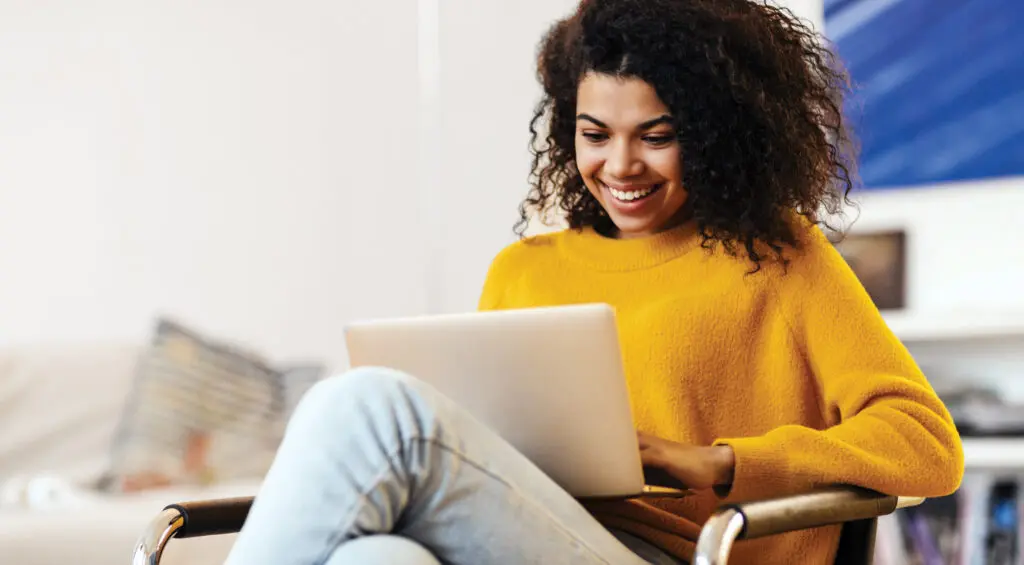 Smiling woman in yellow sweater transacting confidently and securely online.