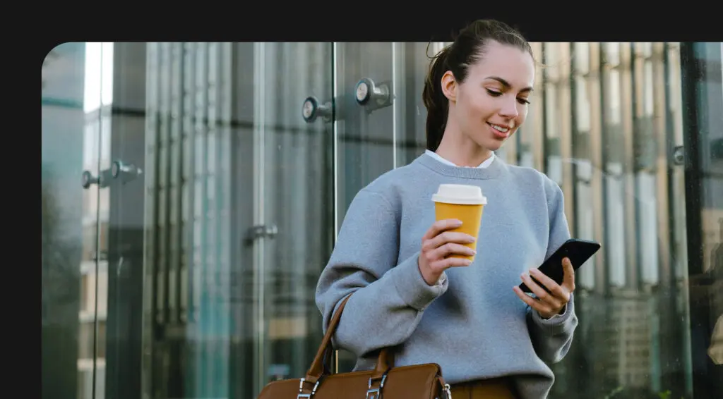 person holding coffee cup looking at phone