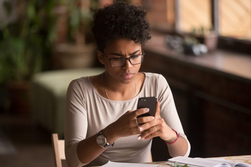 A woman looks intently at a smartphone screen. Avoid e-transfer scams by spotting email fraud.