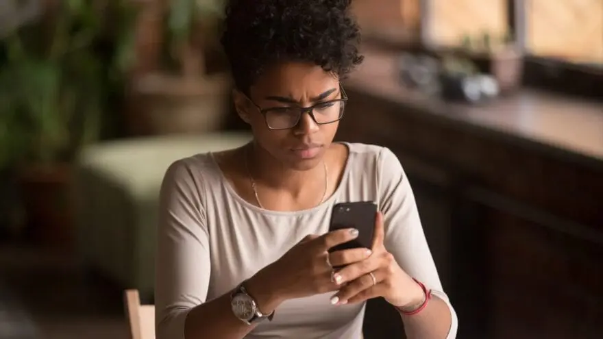 A woman looks intently at a smartphone screen. Avoid e-transfer scams by spotting email fraud.