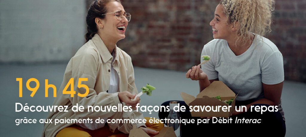 Deux femmes assisses sur le sol prennent un repas acheté avec Débit Interac.