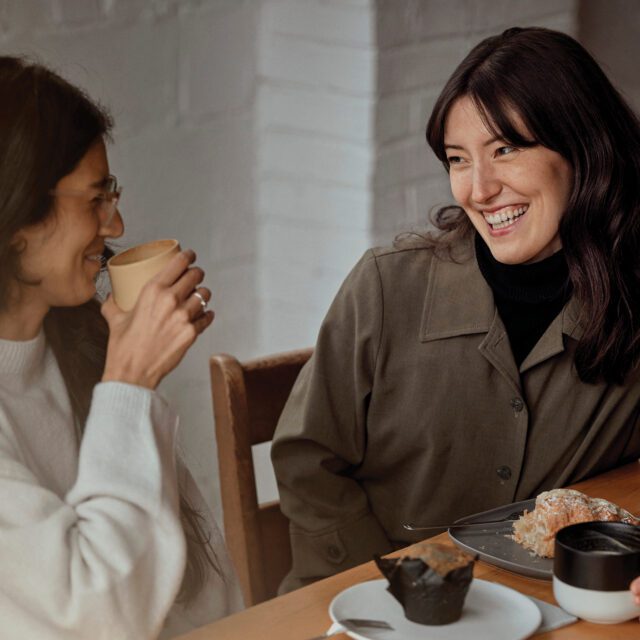 Two women talking about financial independence over coffee.