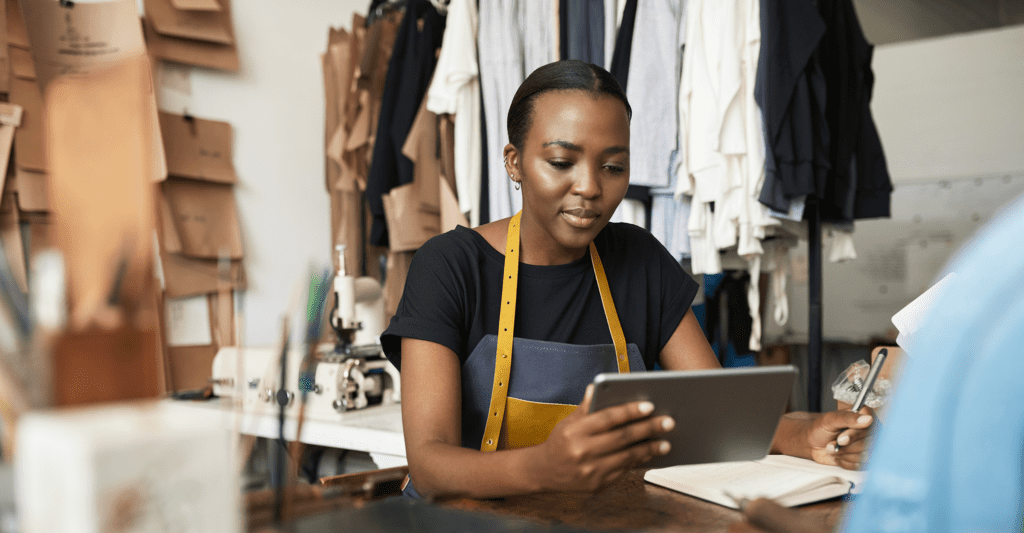 A clothing designer works on her tablet, using fintech solutions to support her small business.