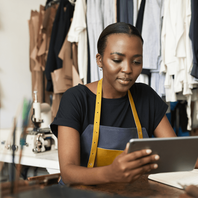 Avenir du détail Interac : Une femme vêtue d’un un tablier dans un atelier tient une tablette.