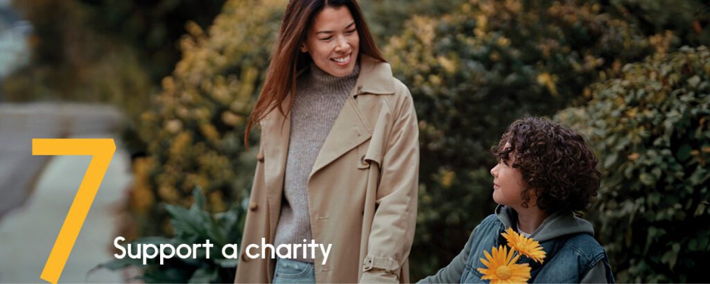A mother and her daughter smile as they enjoy a walk outside holding yellow flowers.