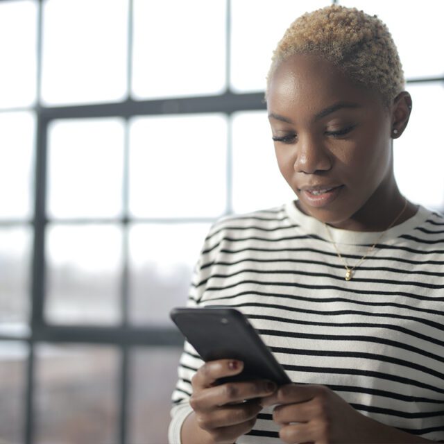 A woman holds a smartphone. COVID-19 has accelerated digital ID, payments modernization and other trends