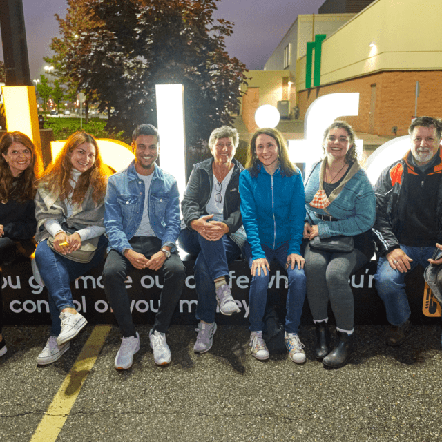 Interac Chief Human Resources Officer Caroline Stephens sits with fellow Interac employees outdoors