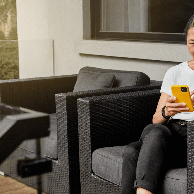 Woman sits on her deck using cellphone. Interac e-Transfer for Business offers safe money transfer