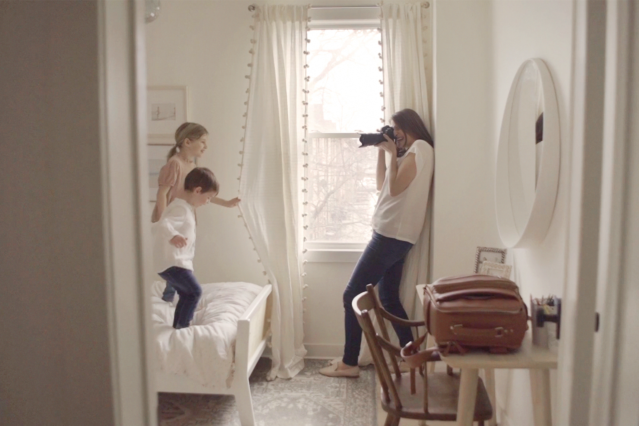 Family photographer Kira Noel takes a picture of two children inside a bedroom.