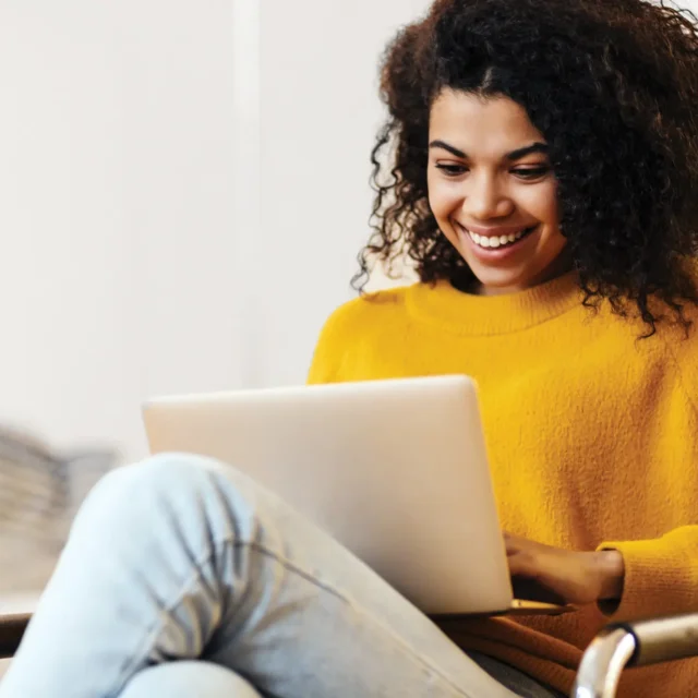 Femme souriante portant un chandail jaune transigeant avec confiance et sécurité en ligne.