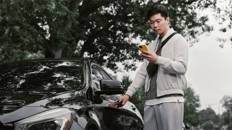 Man beside his car looking at his phone