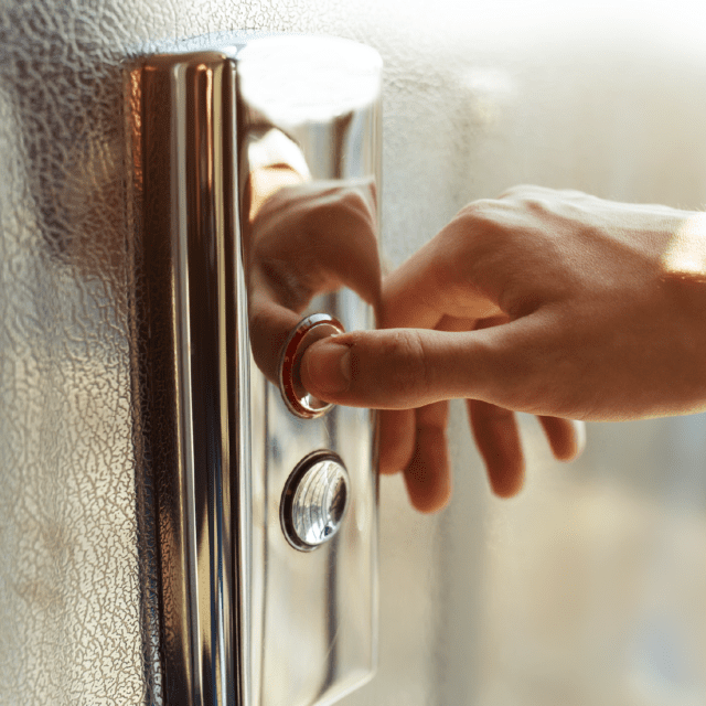 A close up shot of a hand pressing an elevator button