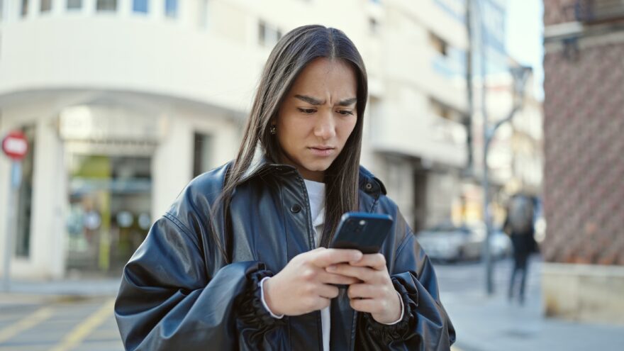 Woman considers safe digital security habits while reading a fraud email on phone